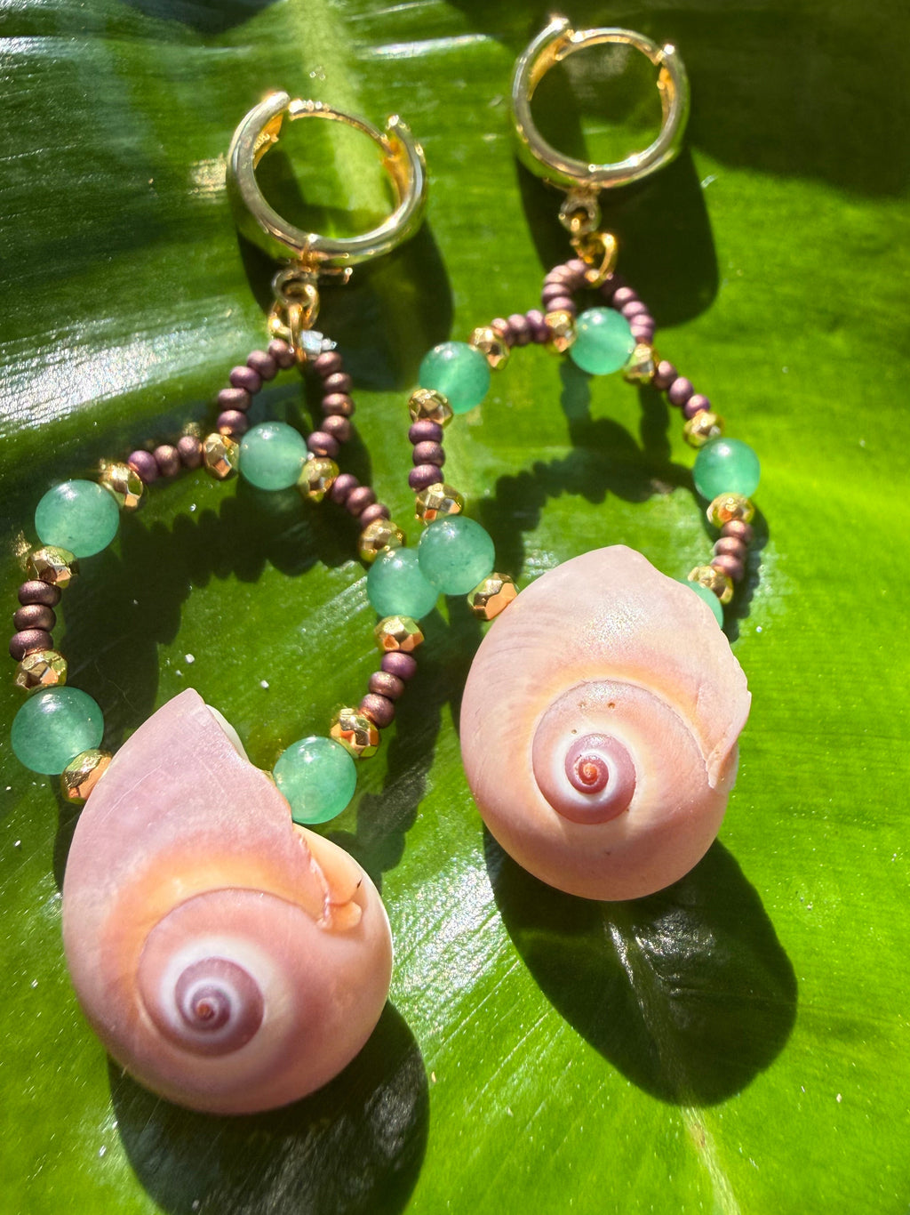 Shark eye earrings with gold, brown and green beads wi th gold cuff hooks.