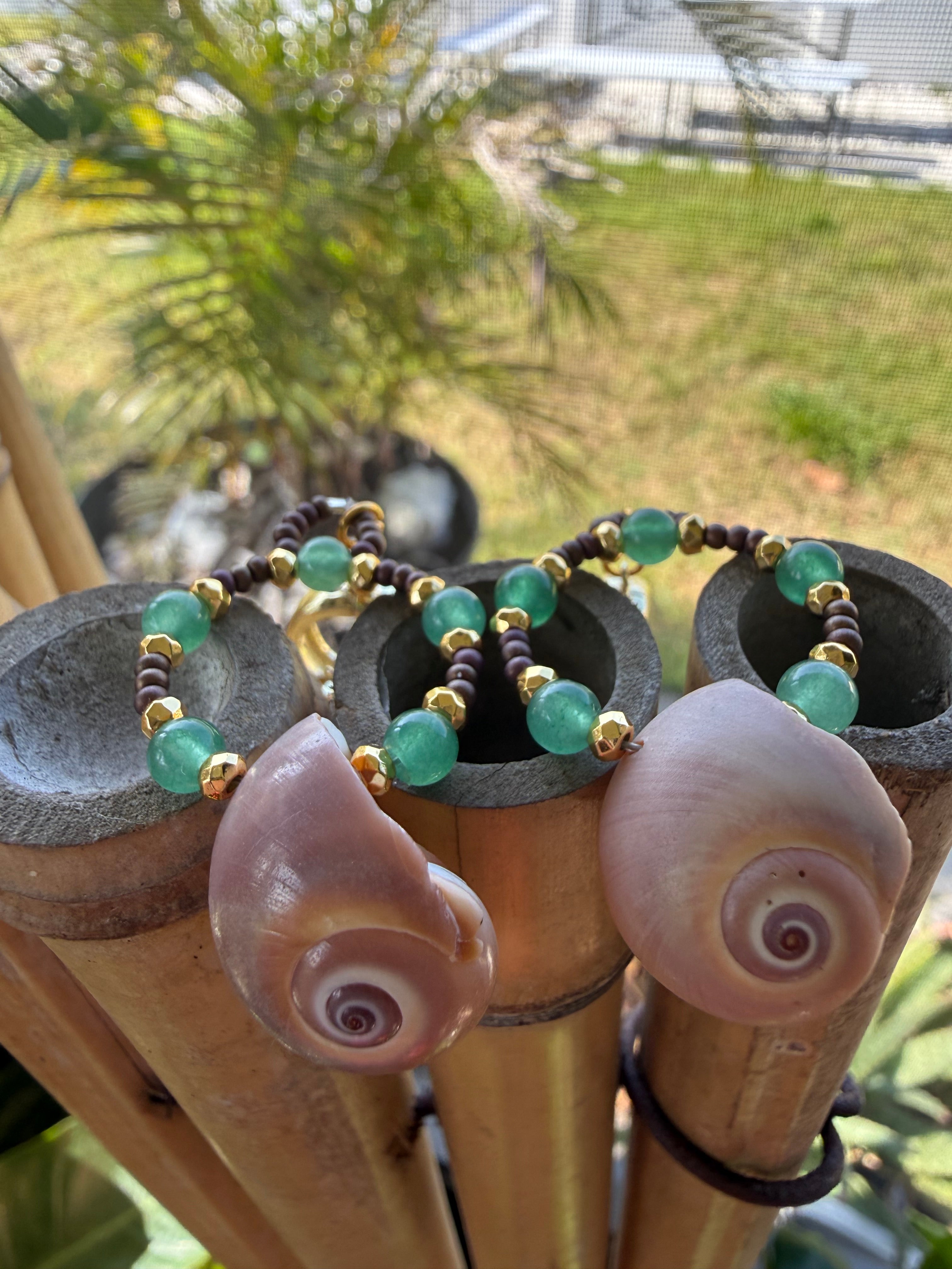 Shark eye earrings with gold, brown and green beads wi th gold cuff hooks.
